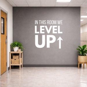 Motivational wall decal 'IN THIS ROOM WE LEVEL UP' on a gray wall in an school setting.