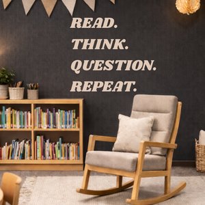 Room with a rocking chair, bookshelf, and motivational decal, Read. Think. Question. Repeat.