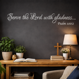 Nestled corner with a wooden table, lamp, cross, and open book against a dark wall with 'Serve the Lord with gladness' text.